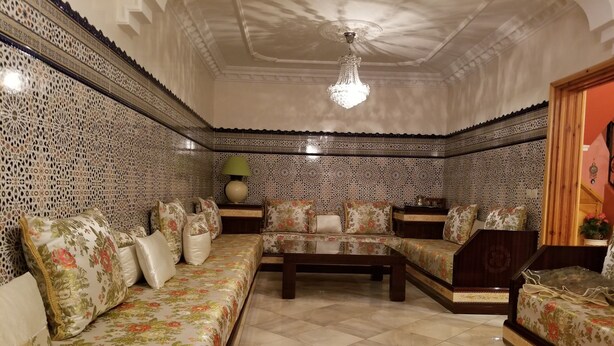 A traditional Moroccan interior with patterned walls, a sofa set, a coffee table, and a chandelier. - Villa of your dreams .. (Agadir)