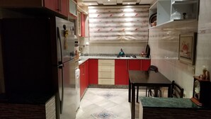 A compact kitchen with red and white cabinetry, a built-in stove, and a dining area with a table and chairs. - Villa of your dreams .. (Agadir)