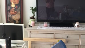 A room with a television, a desk with a computer, a chair, a potted plant, and a framed picture on the wall. - Sea view apartment (Quiberon)