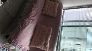 A bedroom with a bed, pillows, a window, and a view of buildings outside. - Sea view apartment (Quiberon)