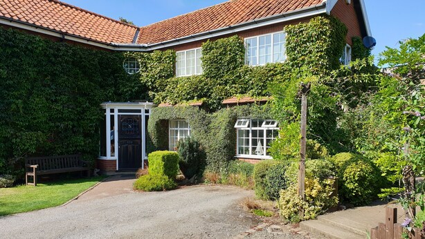 A house with a gravel driveway, a front door, and a bench. - The Summer Room (Norwich)