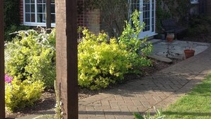 A brick house with a garden, a wooden pergola, and a paved pathway. - The Summer Room (Norwich)