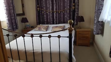 Een slaapkamer met een bed, twee nachtkastjes, een lamp en een dressoir.