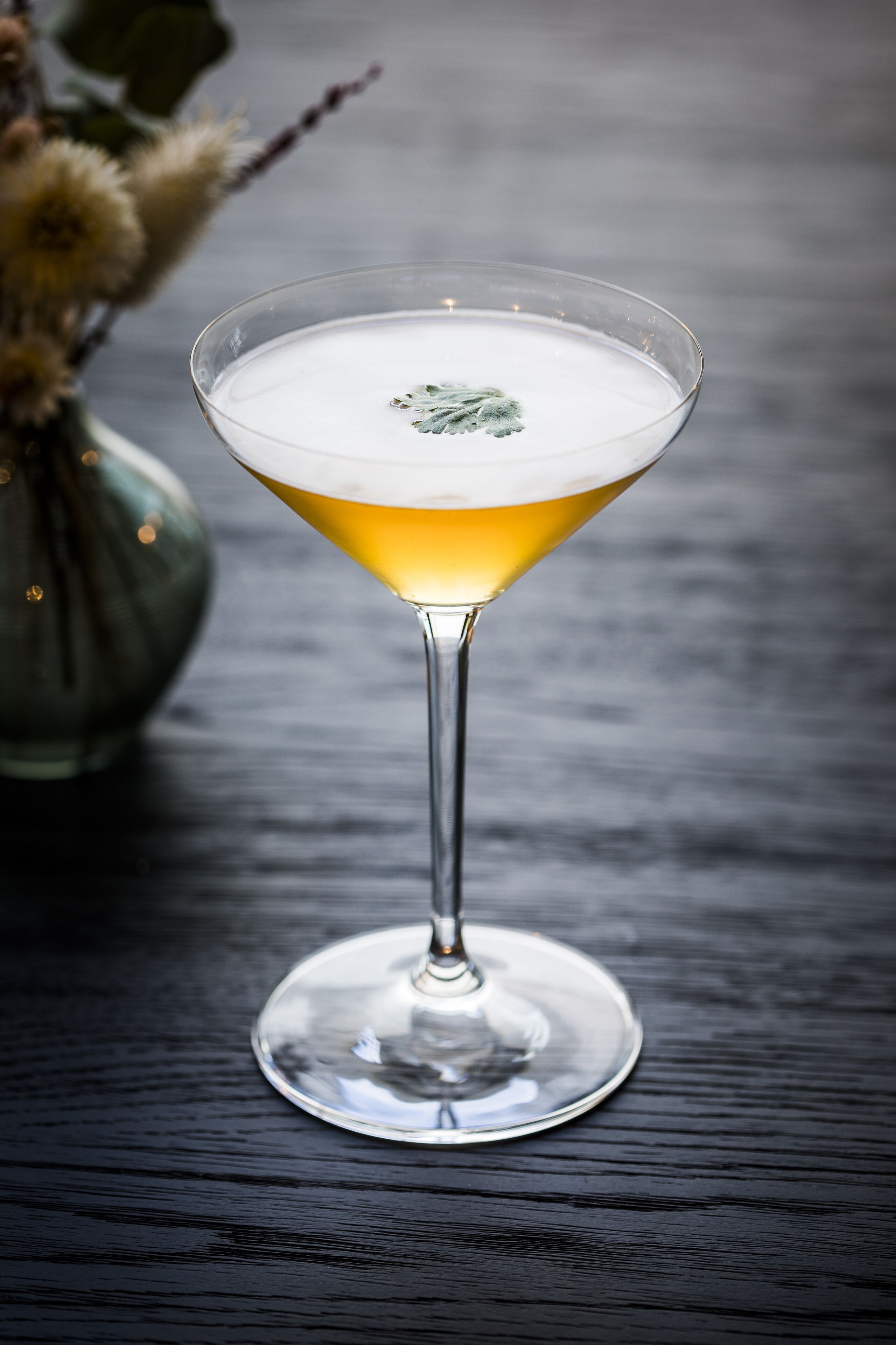 Una copa de martini con un líquido transparente sobre una superficie de madera oscura.
