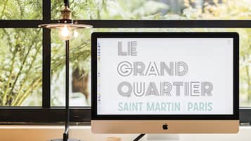Un écran d’ordinateur posé sur un bureau, avec vue sur un bâtiment par la fenêtre.
