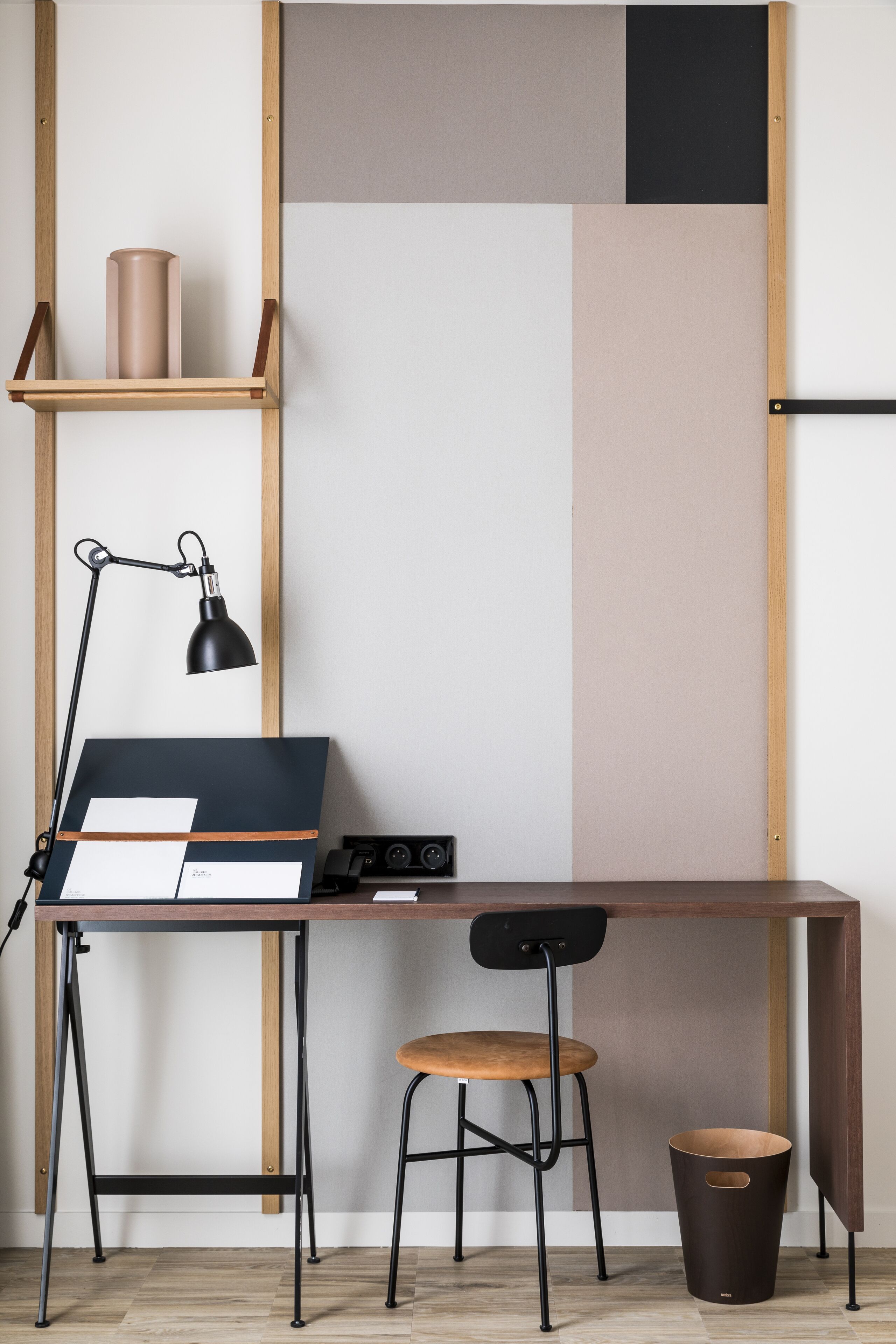 A workspace with a desk, chair, lamp, and storage shelf.
