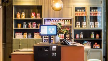 A modern reception area with a central counter, a digital display, and shelves stocked with various products.