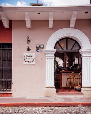 A café named 'Ojala' with a sign, a number '20', and a bar area with chairs. - Ojala (Antigua Guatemala)