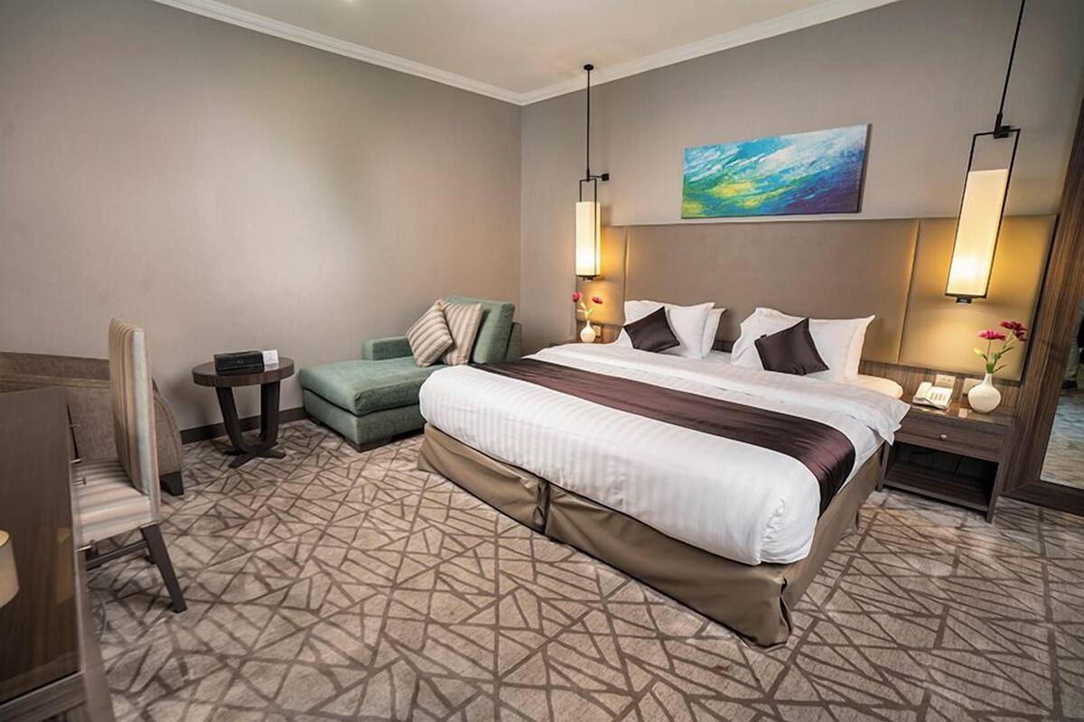 Une chambre d’hôtel avec un grand lit, un bureau, une chaise et une petite table.