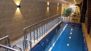 Une piscine intérieure avec un sol carrelé et une rambarde en métal.