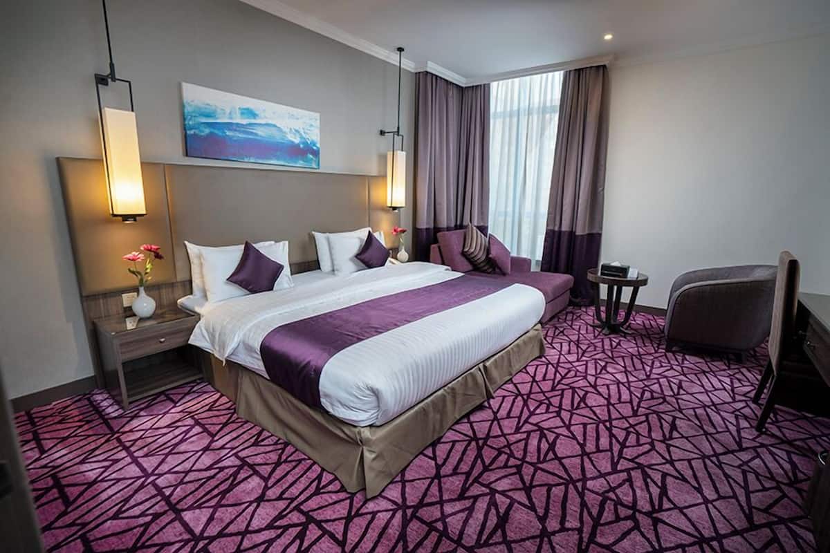 Une chambre d’hôtel avec un grand lit, une table de chevet, une chaise et un bureau.