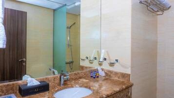 Un bagno con lavabo in marmo, uno specchio, un porta asciugamani e una zona doccia.