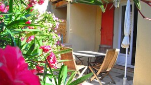 An outdoor patio with a table and chairs, surrounded by lush greenery and vibrant flowers. - Les Mazets Du Soleil: Bed and Breakfast (Maussane-les-Alpilles)