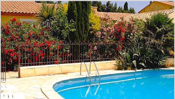 A swimming pool with a metal ladder, surrounded by a tiled deck and a metal fence. - Les Mazets Du Soleil: Bed and Breakfast (Maussane-les-Alpilles)