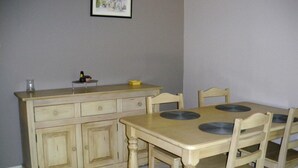 A dining area with a wooden table and chairs, a cabinet with drawers, and a framed picture on the wall. - Les Mazets Du Soleil: Bed and Breakfast (Maussane-les-Alpilles)
