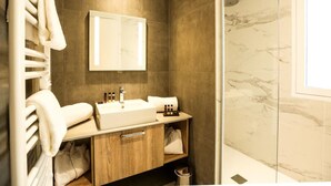 Ein modernes Badezimmer mit einem großen Spiegel, einem Waschbecken und einem Handtuchhalter.