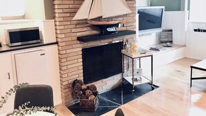 A living room with a brick fireplace, a television, and a bookshelf.