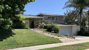 A two-story house with a stone facade, a front yard with a stone pathway, and a garage.