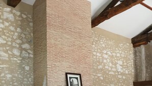 A rustic interior with exposed stone walls, a fireplace with a mantel, and wooden furniture.