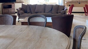 A stone-walled room with a round wooden table, a sofa, and a television.
