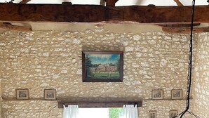A rustic living room with a stone wall, wooden beams, a sofa, a coffee table, a TV, and a foosball table. - Private gite for rent in a wine estate (Sigoulès)