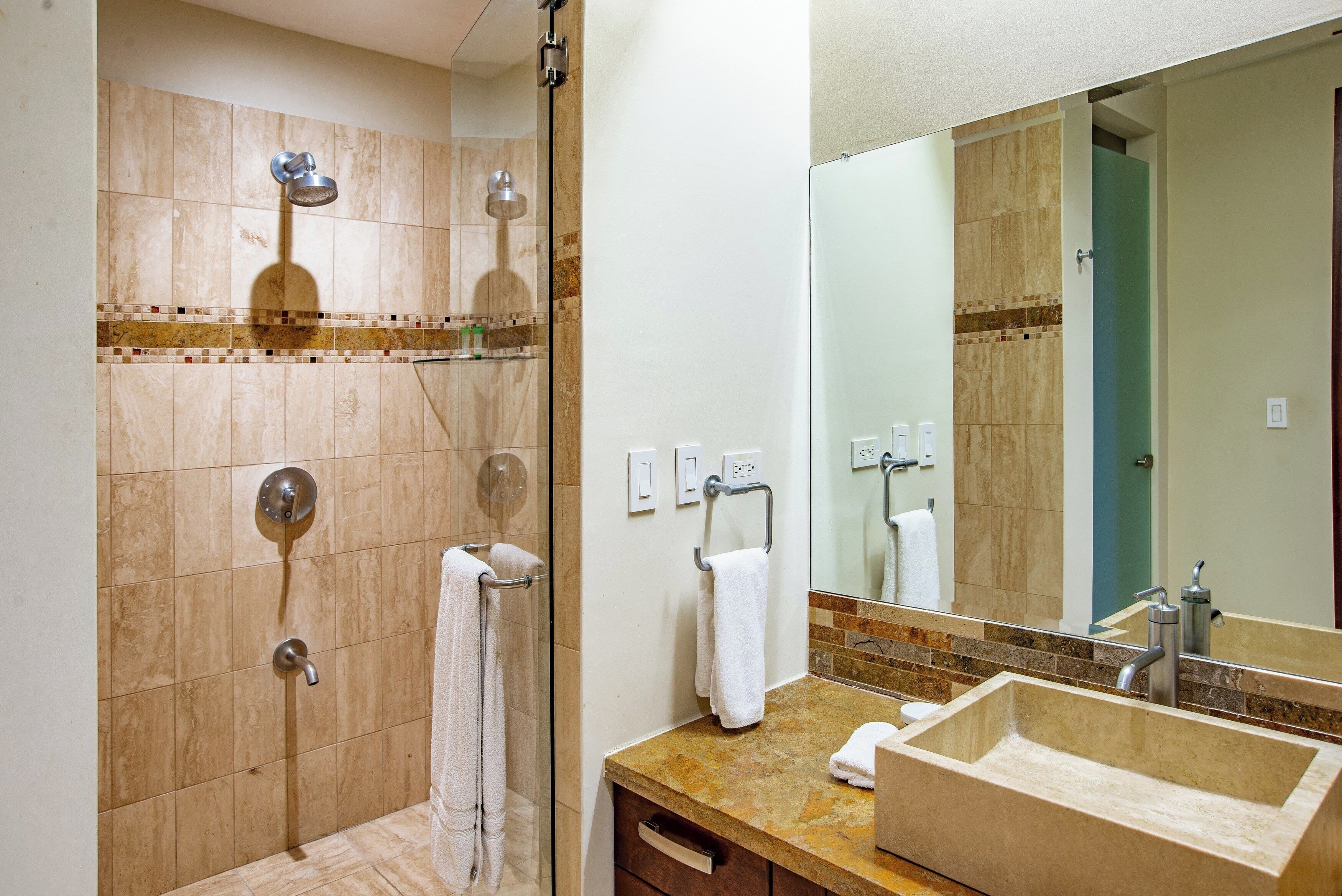 A bathroom with a shower, a sink, and a mirror.
