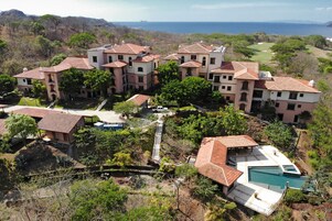 Un grande resort con diversi edifici, una piscina e un campo da golf sullo sfondo.
