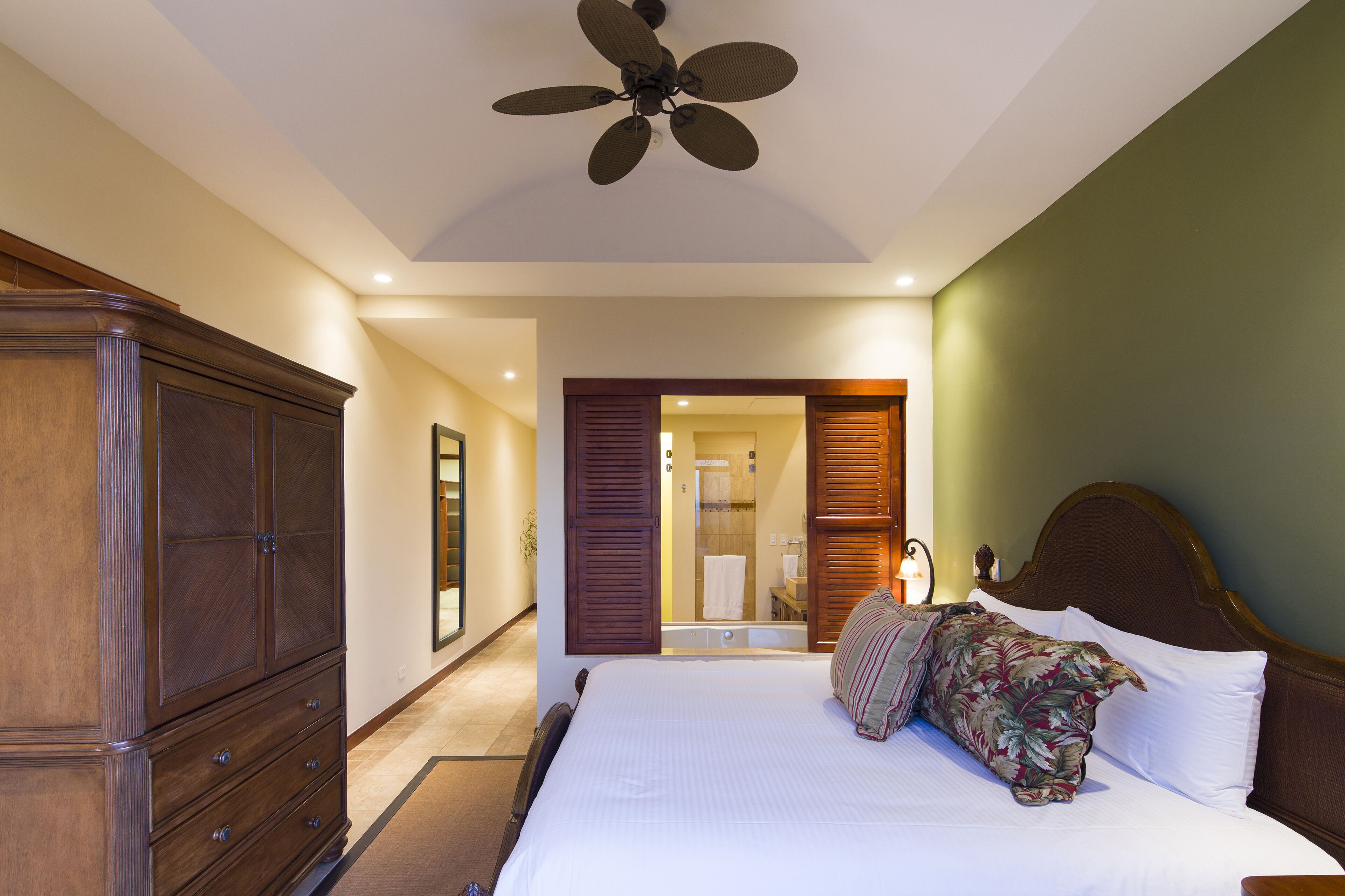 Ein Schlafzimmer mit einem großen Bett, einem Holzschrank und einem Deckenventilator.