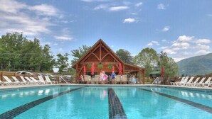 Ein Schwimmbecken mit Liegestühlen und einem Holzpavillon im Hintergrund.