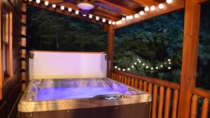 Ein Whirlpool in einem hölzernen Pavillon mit Lichterketten, umgeben von Bäumen.