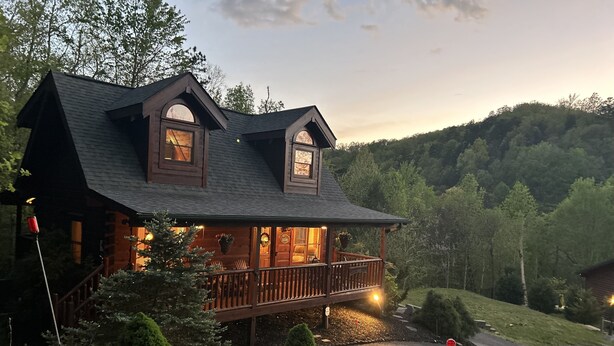 Eine Blockhütte mit Veranda, großen Fenstern und einer Terrasse.