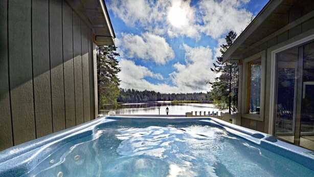 A hot tub with a view of a lake and trees.