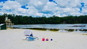 A beach with a chair, a bucket, and a ball.