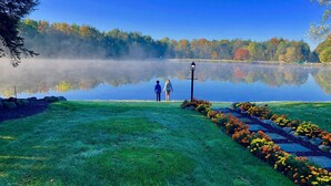 A serene lakeside scene with a clear view of the lake, a pathway leading to the water, and a lamp post.