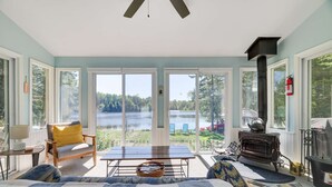 A cozy room with a large window, a fireplace, and a view of a lake.
