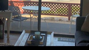 A room with a view of a desert landscape, palm trees, and a building in the distance. There is a ceiling fan and a sign that reads "OUR HAPPY PLACE".