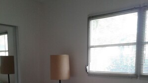 Ein Schlafzimmer mit Bett, Stuhl, Lampe und Fenster.