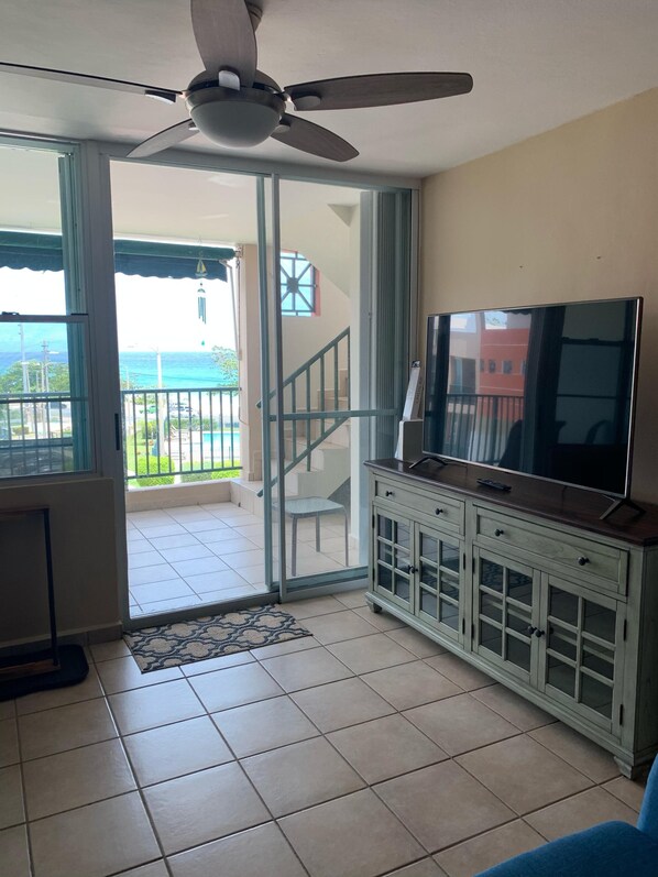A living room with a TV, a ceiling fan, a sliding glass door leading to a balcony, and a staircase. - Arecibo, Puerto Rico (Playa Islote) (Arecibo)