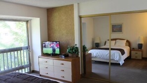 A hotel room with a bed, a TV on a dresser, a mirror, and a view of the outdoors. - 2 bed condo Thunderbird Resort Club - Sparks (Sparks)