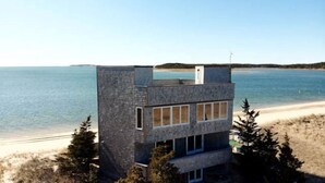 Un edificio moderno con techo plano, grandes ventanales y vista al mar.