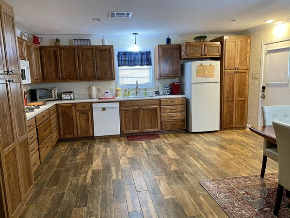 Una cocina con armarios de madera, un refrigerador blanco, un microondas y un tostador.
