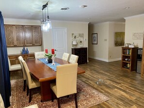 A dining area with a wooden table, beige chairs, a blue placemat, and a chandelier.