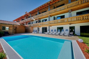 Una piscina con sillones de descanso y un balcón de madera.