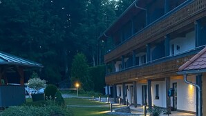 Une cour avec un chemin pavé, un petit jardin et un bâtiment doté d’un balcon.