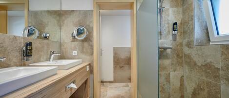 Un baño moderno con dos lavamanos, ducha y un espejo grande.
