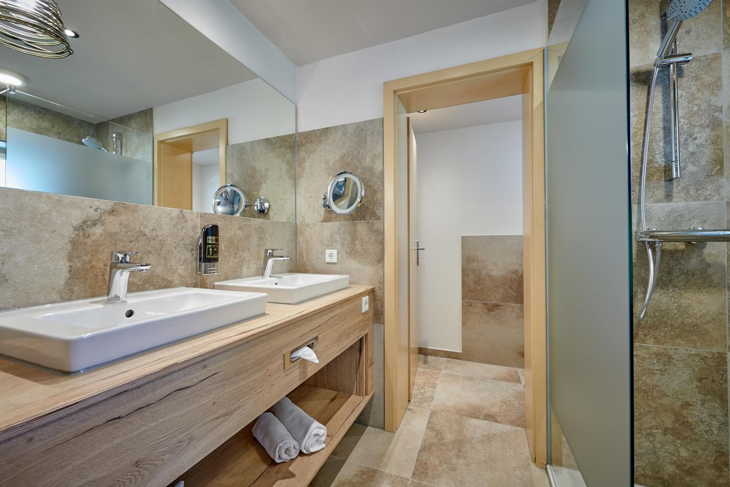 Un baño moderno con dos lavamanos, un espejo y una ducha.