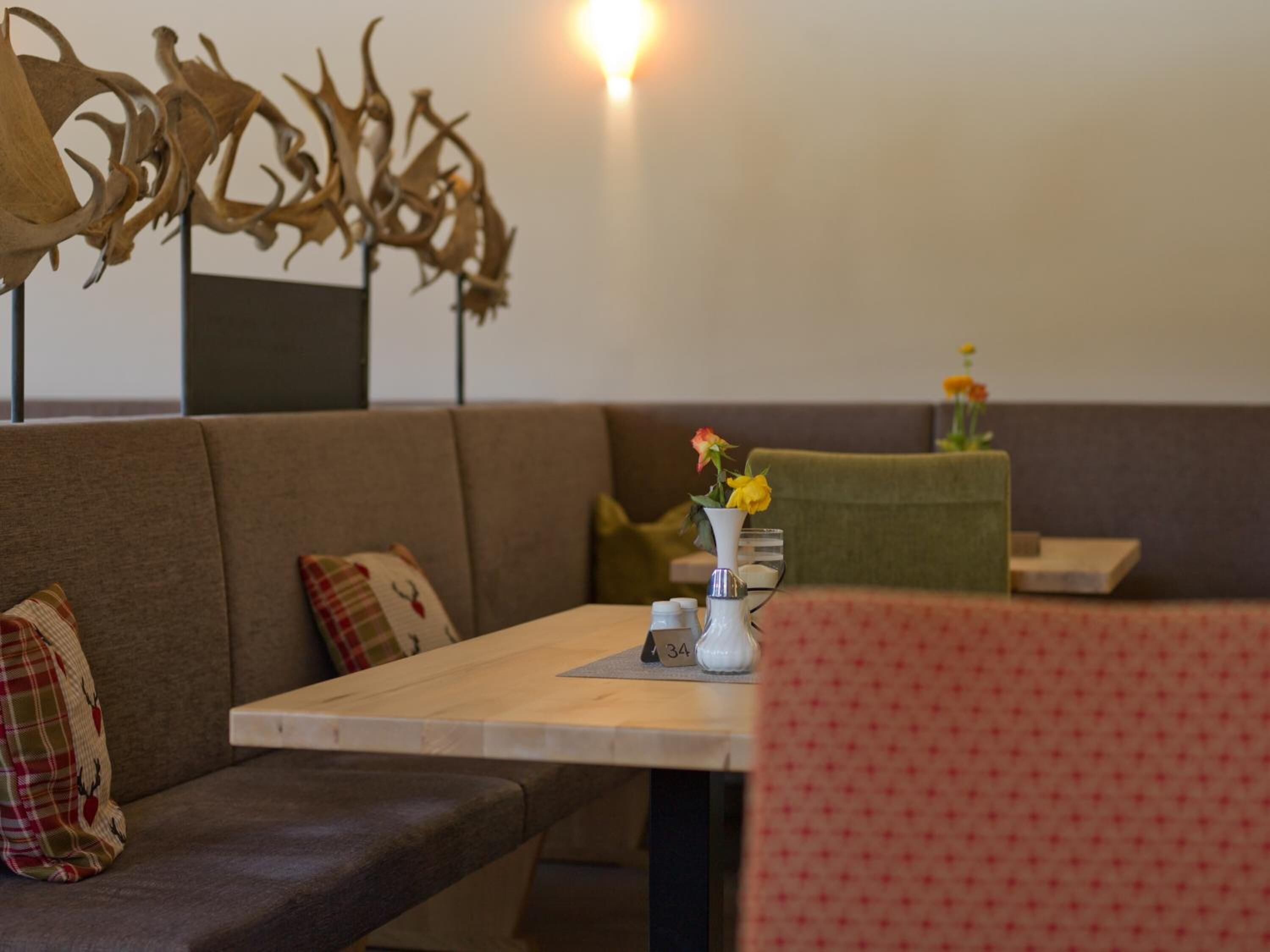 A cozy seating area with a wooden table, a vase with flowers, and a decorative wall piece.