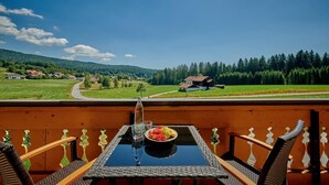 Un balcon avec une table, des chaises et une vue sur un paysage rural.