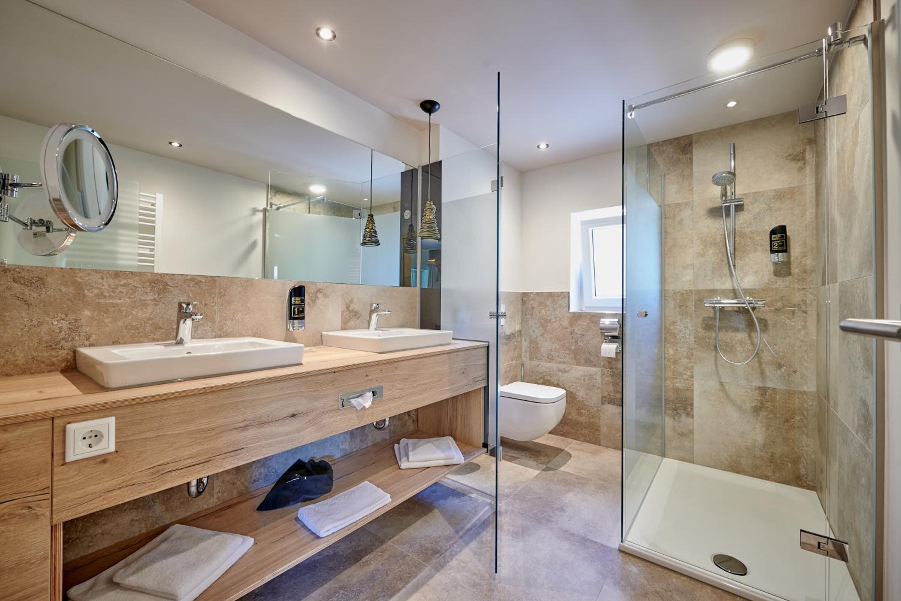 A modern bathroom with two sinks, a glass shower enclosure, and a large mirror.