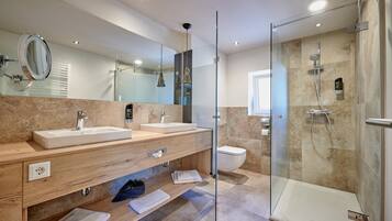 A modern bathroom with two sinks, a glass shower enclosure, and a large mirror.